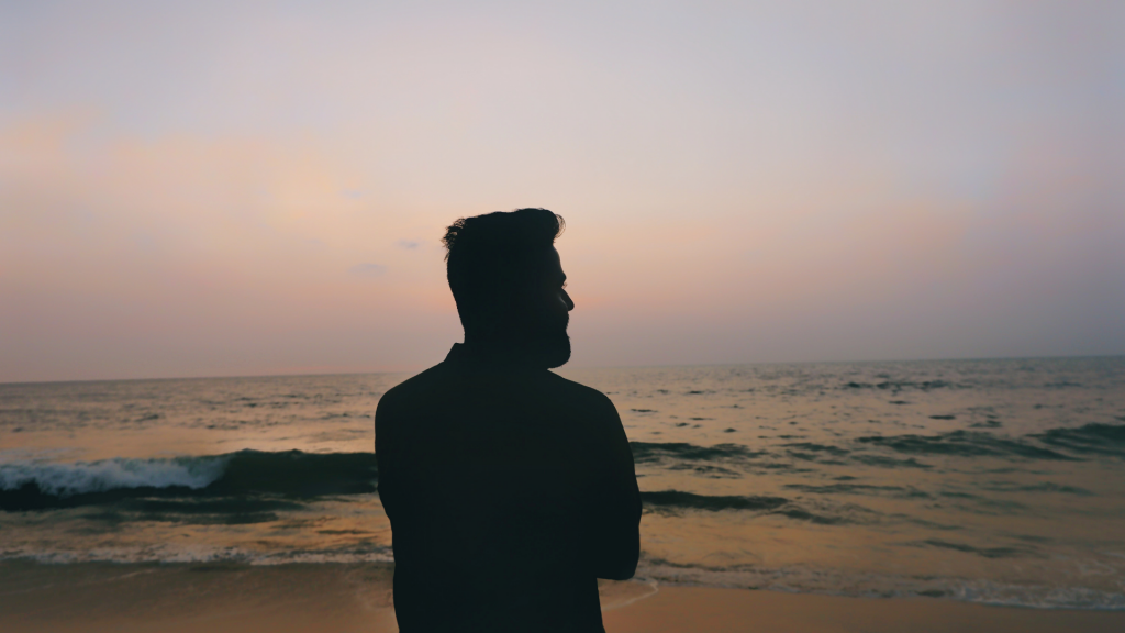 Um homem em pé à beira da praia.