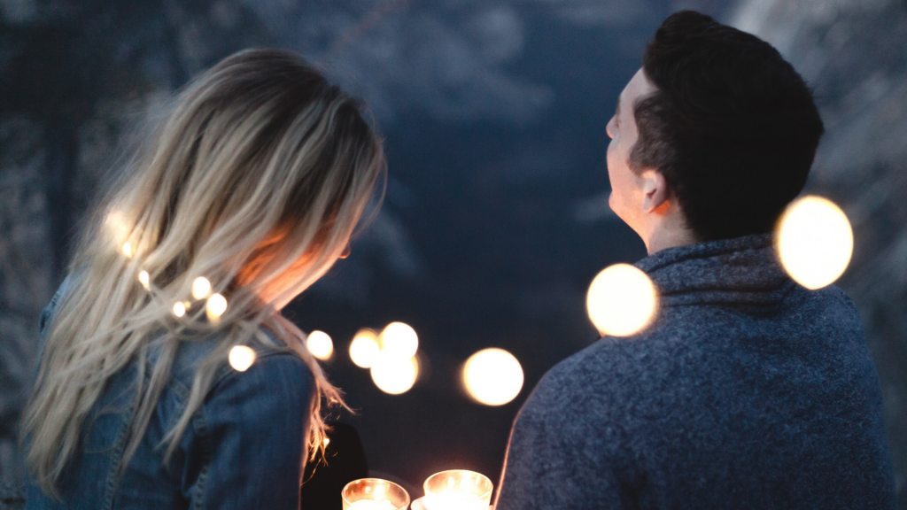 Um casal heterossexual rodeado por luzes e velas.