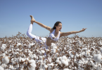 Mulher em um campo de algodão fazendo Yoga.