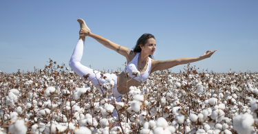 Mulher em um campo de algodão fazendo Yoga.