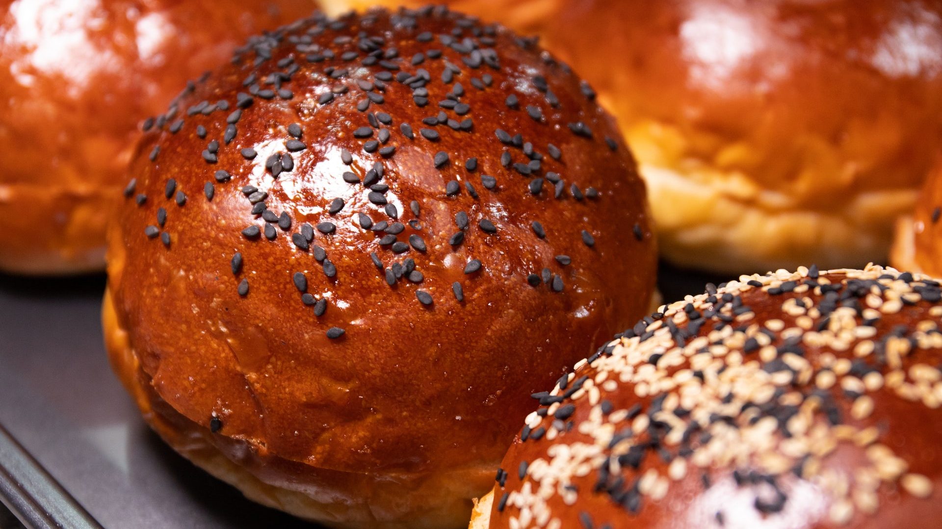 Pão brioche tostadinho com gergelim preto em cima.