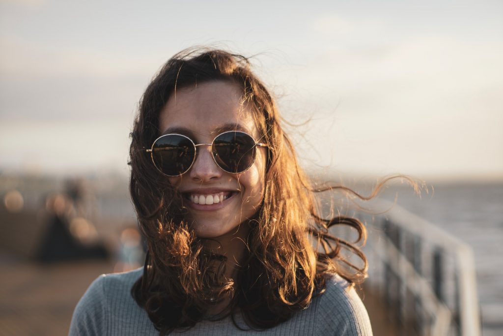 Mulher branca sorrindo com cabelos ao vento.