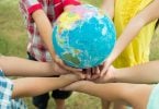 Crianças segurando um globo que representa o planeta terra.
