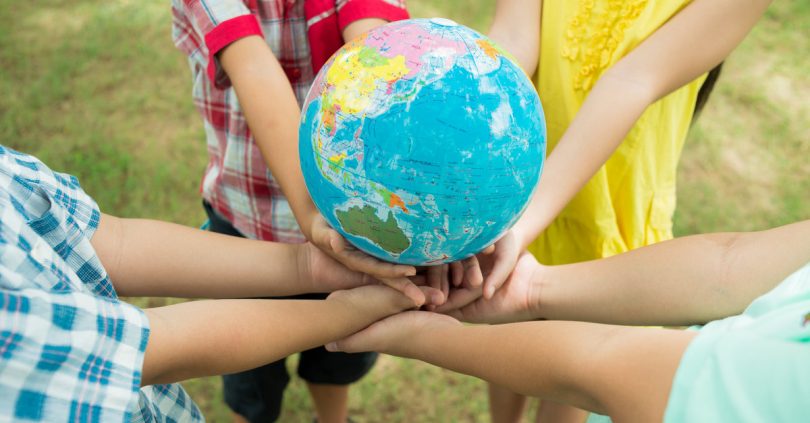 Crianças segurando um globo que representa o planeta terra.