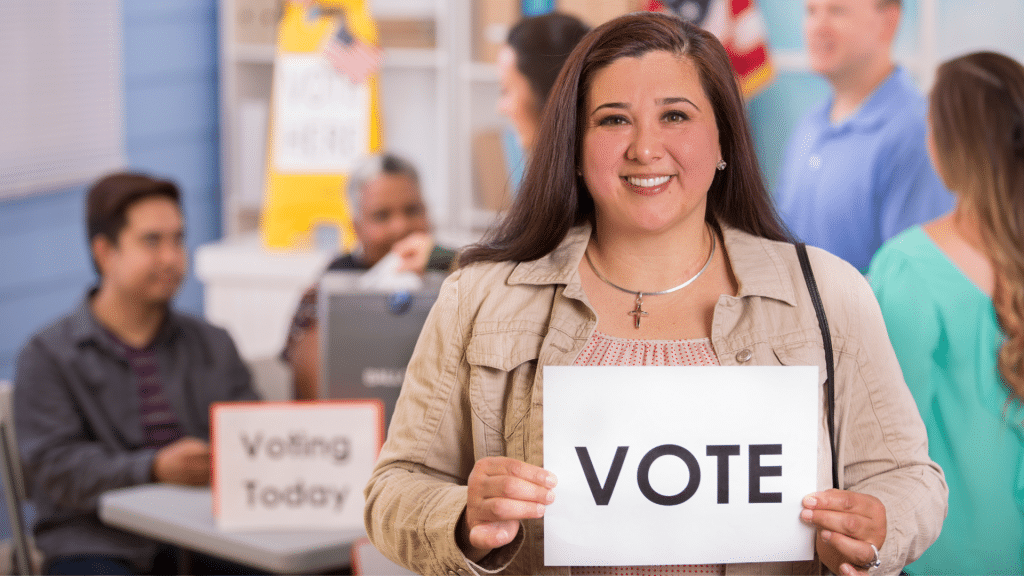 Uma mulher segurando uma placa branca que contém a palavra "vote" escrita. 