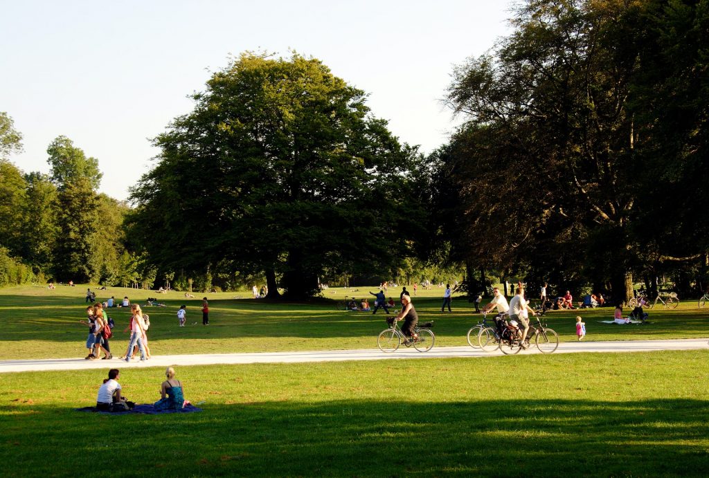 Pessoas andando a pé e de bicicleta em um parque.