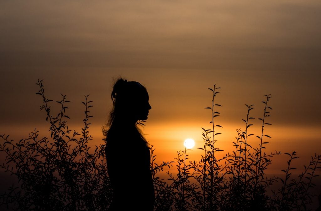 Silhueta de uma mulher em um pôr do sol.