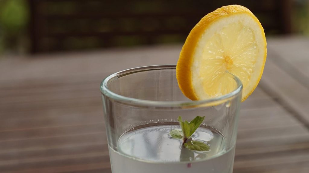 Copo de água com uma rodela de limão encaixada na borda