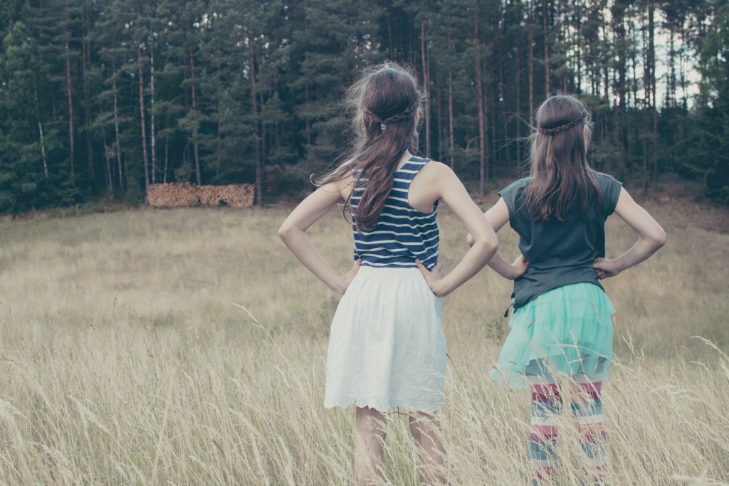 Duas garotas em meio a natureza fazendo a pose de poder de super-herói