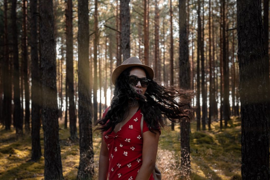 Mulher negra balançando os cabelos em bosque.
