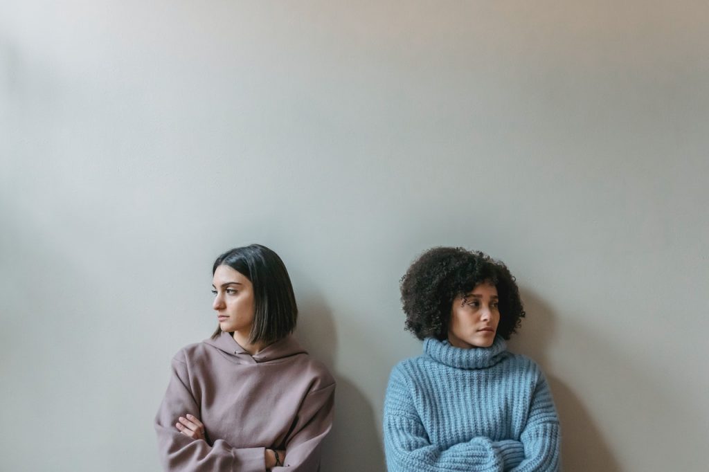 Duas meninas de cara virada uma para outra. Ambas estão com semblantes raivosos.