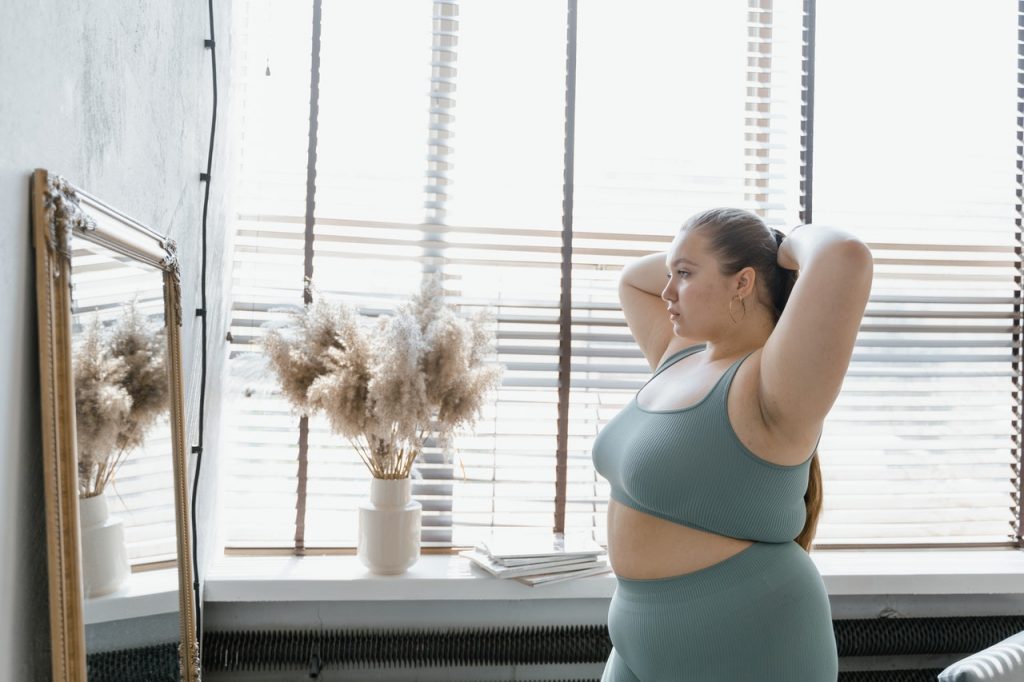 Mulher plus size se olhando no espelho com um semblante de confiança.