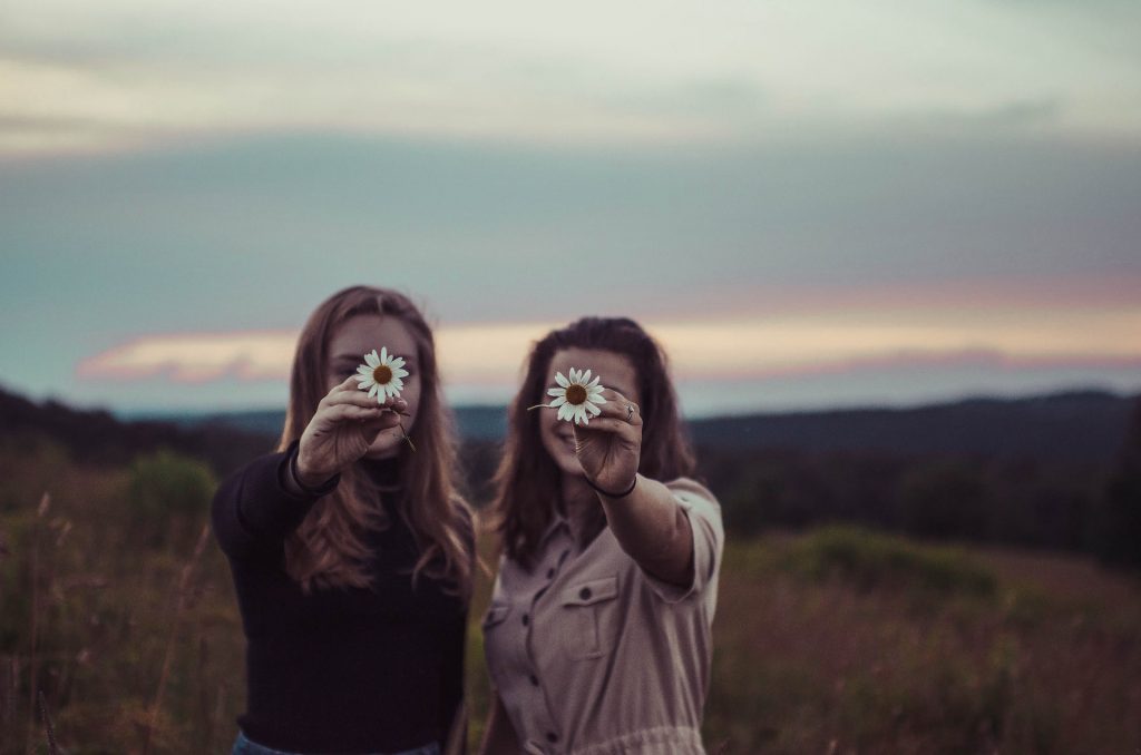 Duas mulheres segurando margaridas.