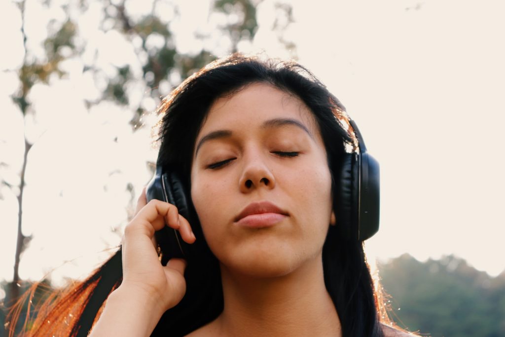 Menina com fones de ouvido e olhos fechados.