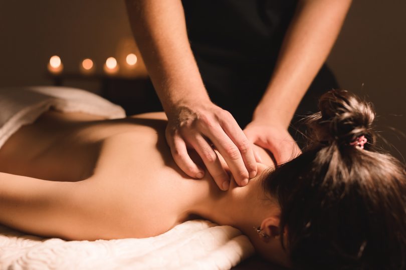 Mulher branca recebendo massagem nas costas.