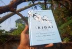 Mão humana segurando um livro cujo o escrito "Ikigai" está na capa.