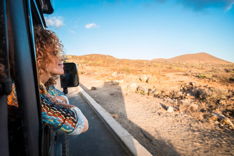 De dentro de um carro, uma mulher observando um trajeto montanhoso.