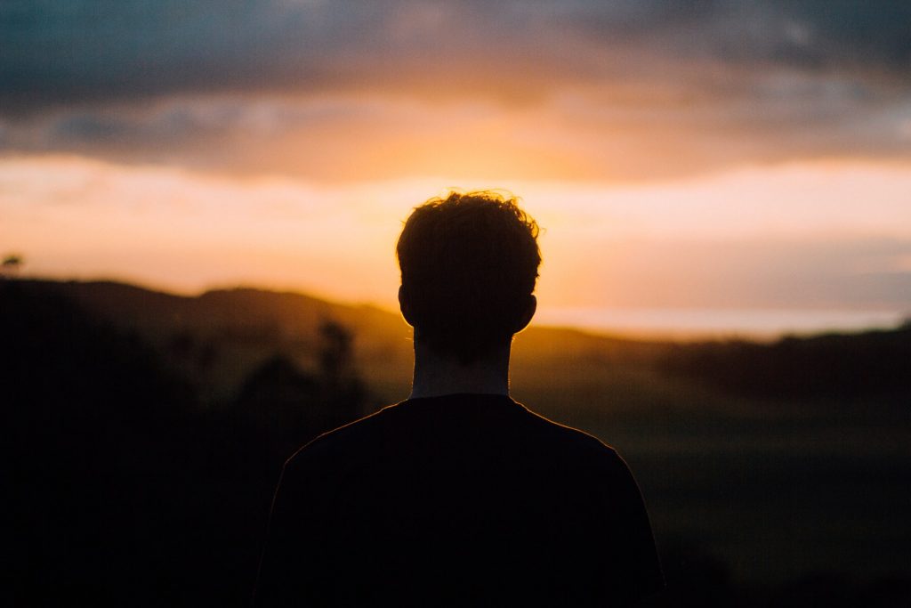 Homem de costas num pôr do sol.