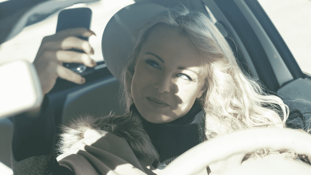 Mulher ao volante tirando uma selfie no carro simbolizando o narcisismo 
