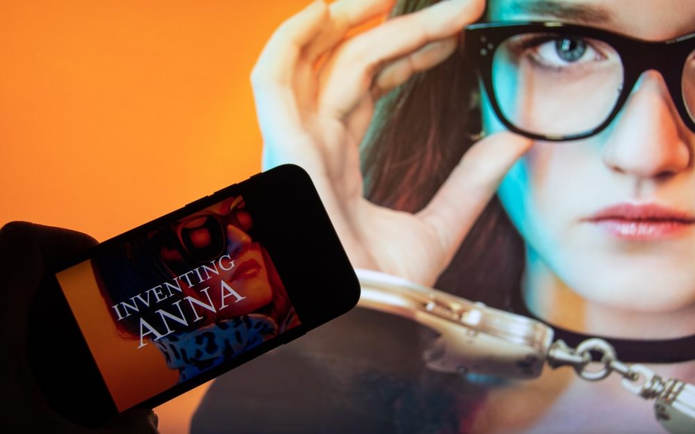 À esquerda, uma mulher que representa Anna Sorokin. À direita, um celular que exibe uma imagem. Esta, por sua vez, tem a frase "Inventing Anna" e, ao fundo, uma fotografia de uma mulher que representa Anna.