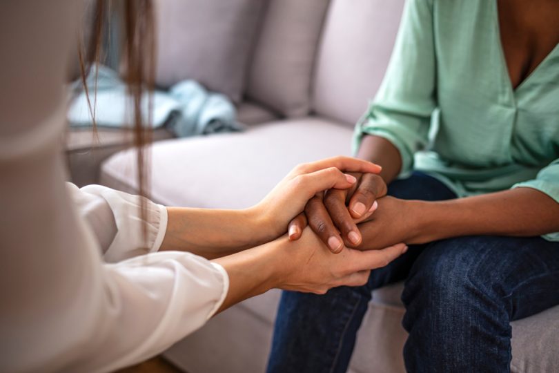 Duas mulheres dão suas mãos uma a outra.