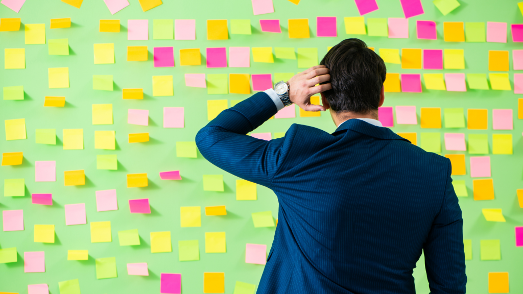 Um homem confuso observando vários pequenos post-its.