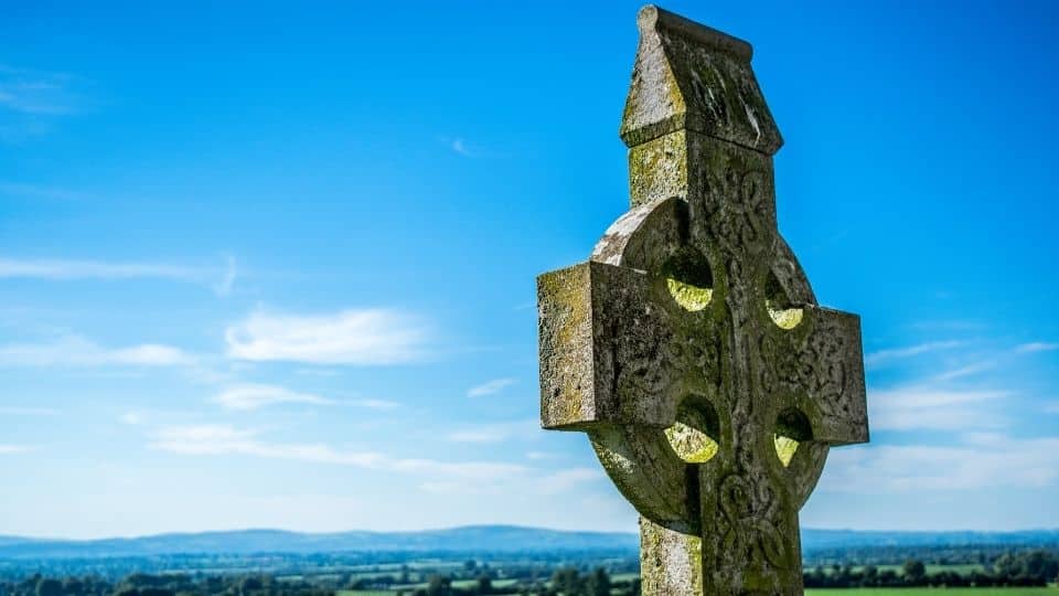 Uma cruz celta de concreto situada numa planície.