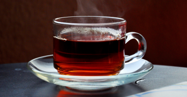 Uma pequena caneca contendo chá quente.