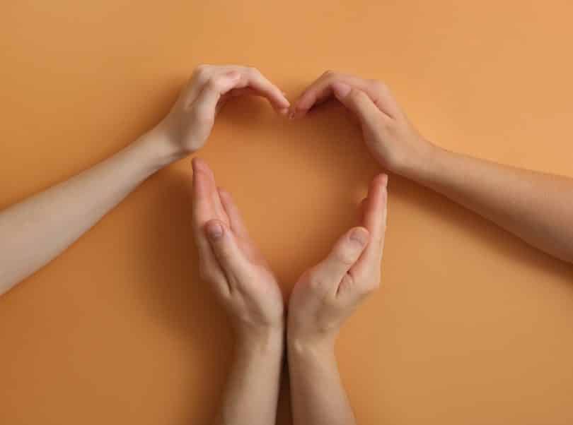 Mãos de pessoas formando um coração.