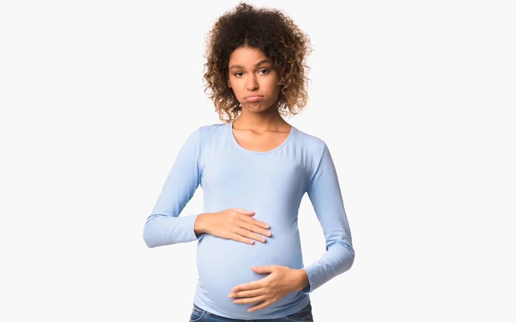 Uma mulher grávida apalpando sua barriga.