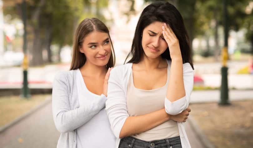 Duas mulheres. À esquerda, uma com um semblante maldoso. À direita, outra que parece se lamentar de algo.