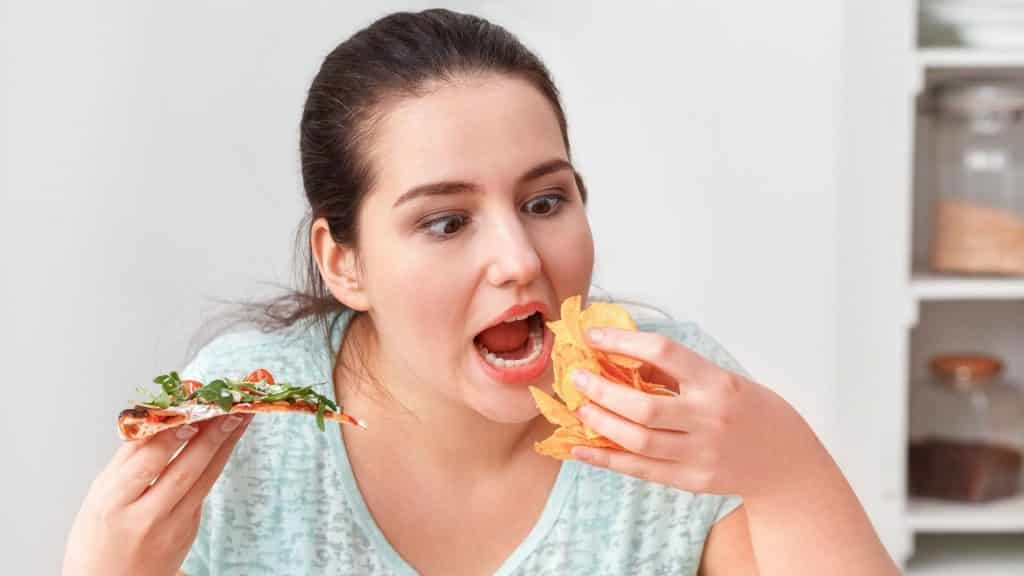 Uma mulher de olhos arregalados comendo nachos.