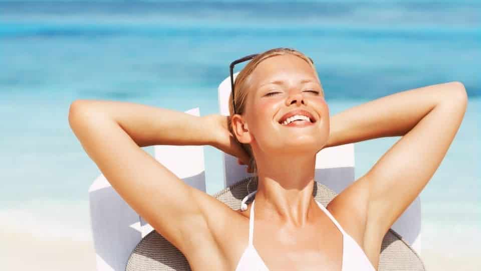 Uma mulher tomando banho de sol numa praia.