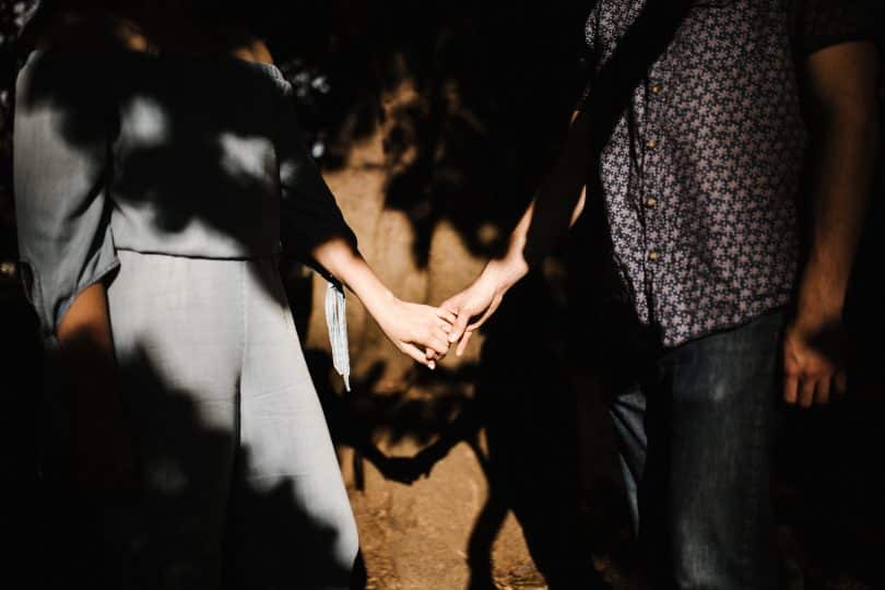 Homem e mulher brancos de mãos dadas.