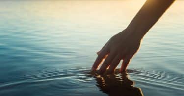 Uma mão imergindo-se num vasto mar.