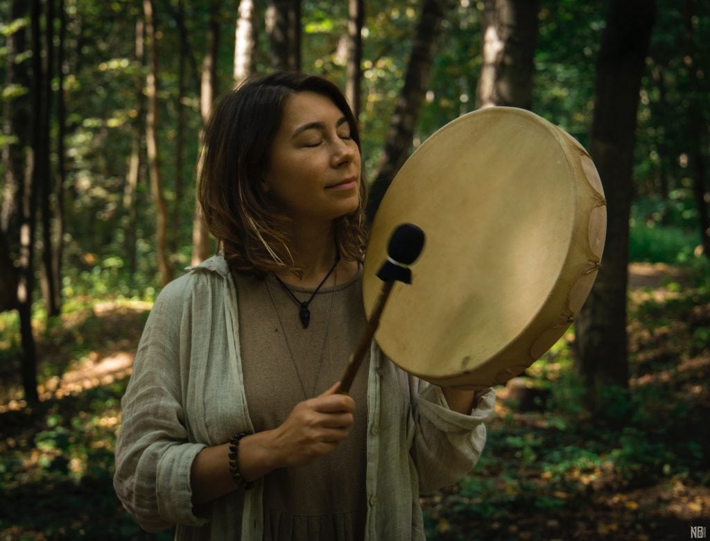 Mulher na floresta tocando tambor.