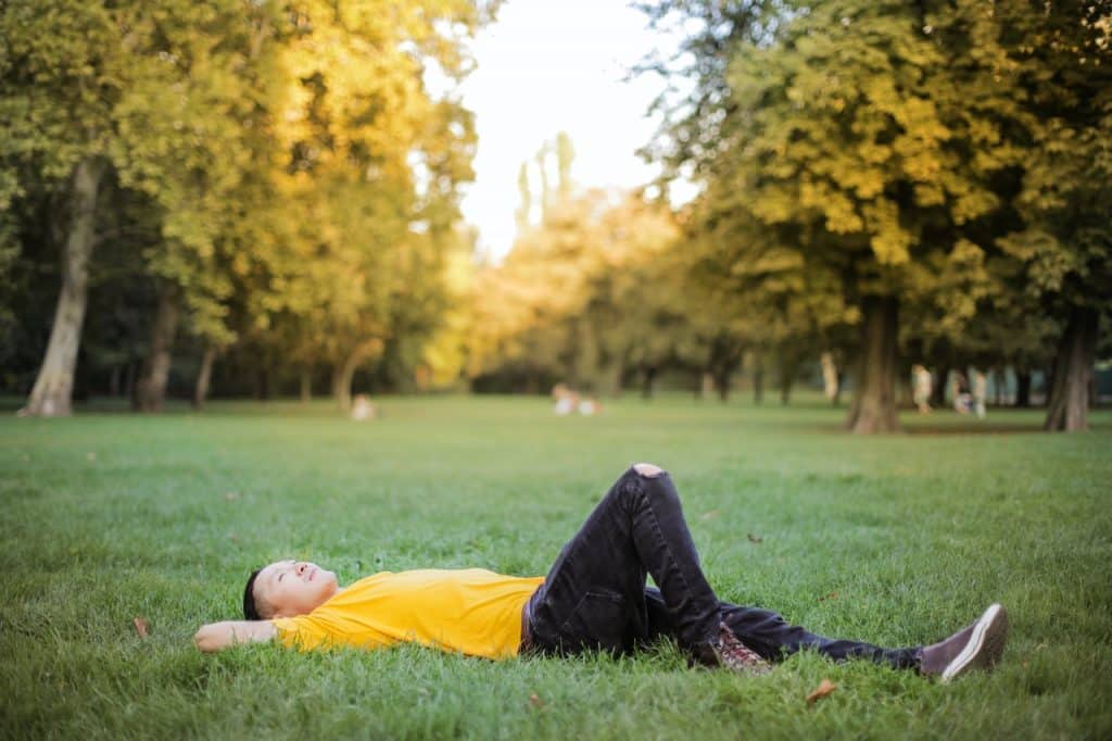 Homem asiático deitado numa grama.