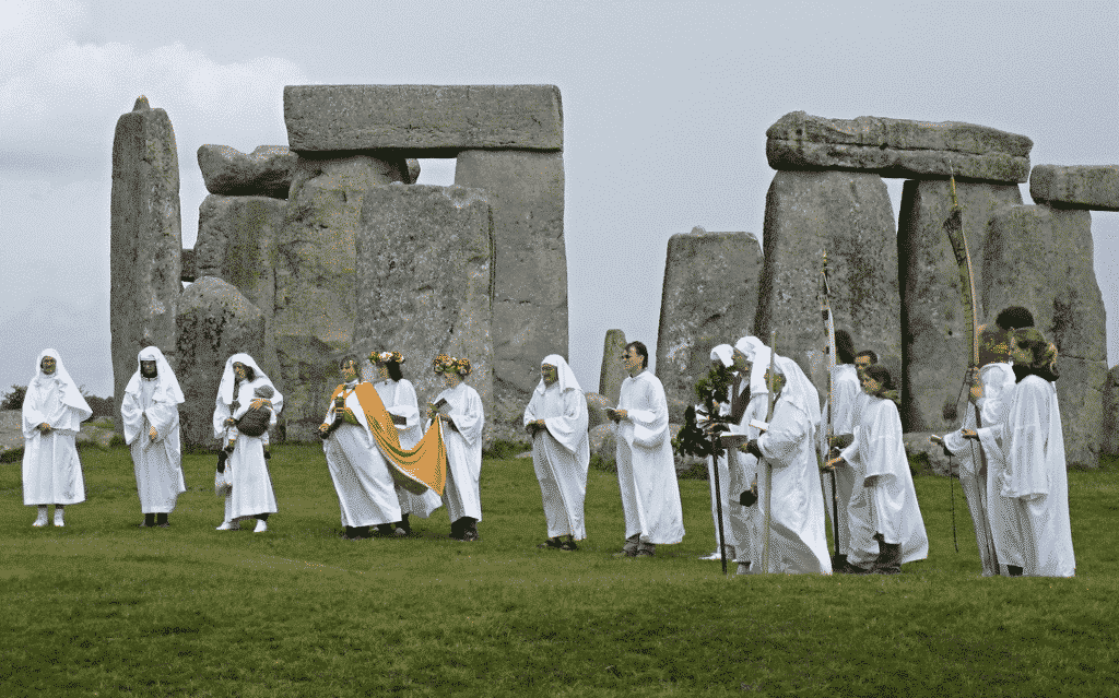 Pessoas de branco reunidas em frente a um stonenge.