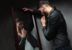 Homem narcisista apoiado no espelho se admirando