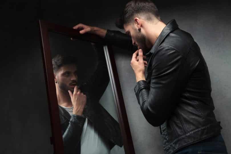 Homem narcisista apoiado no espelho se admirando