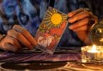 Pessoa segurando a carta "O sol" do tarot