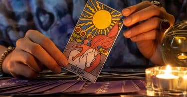 Pessoa segurando a carta "O sol" do tarot