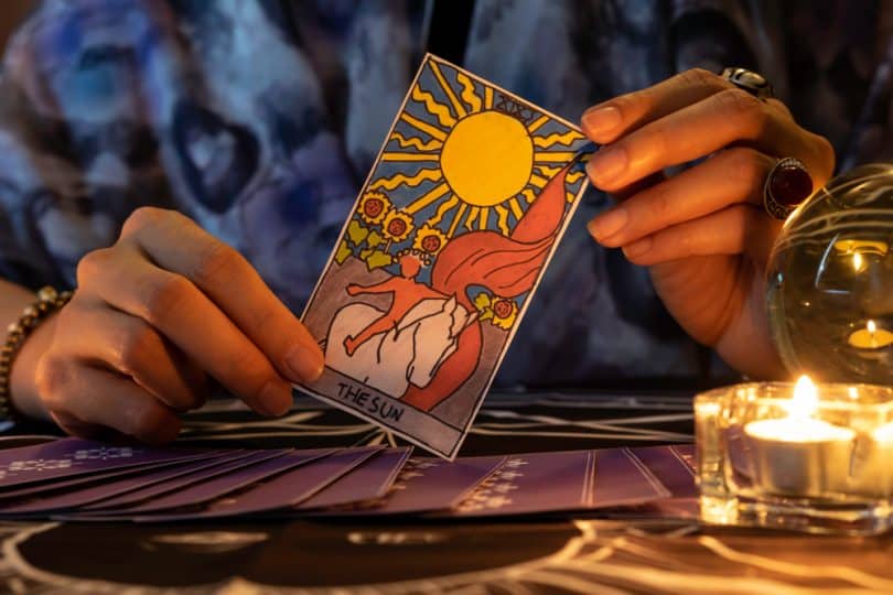 Pessoa segurando a carta "O sol" do tarot