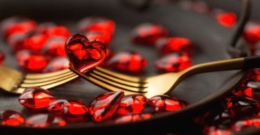 Garfos de ouro em um prato com mini gelatinas em formato de coração.
