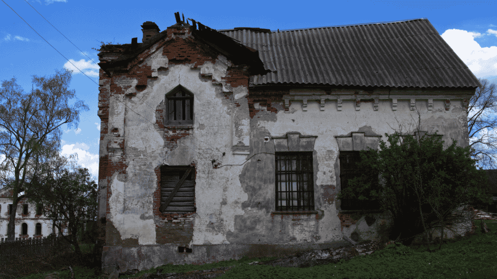Casa velha com os tijolos aparecendo em meio ao campo