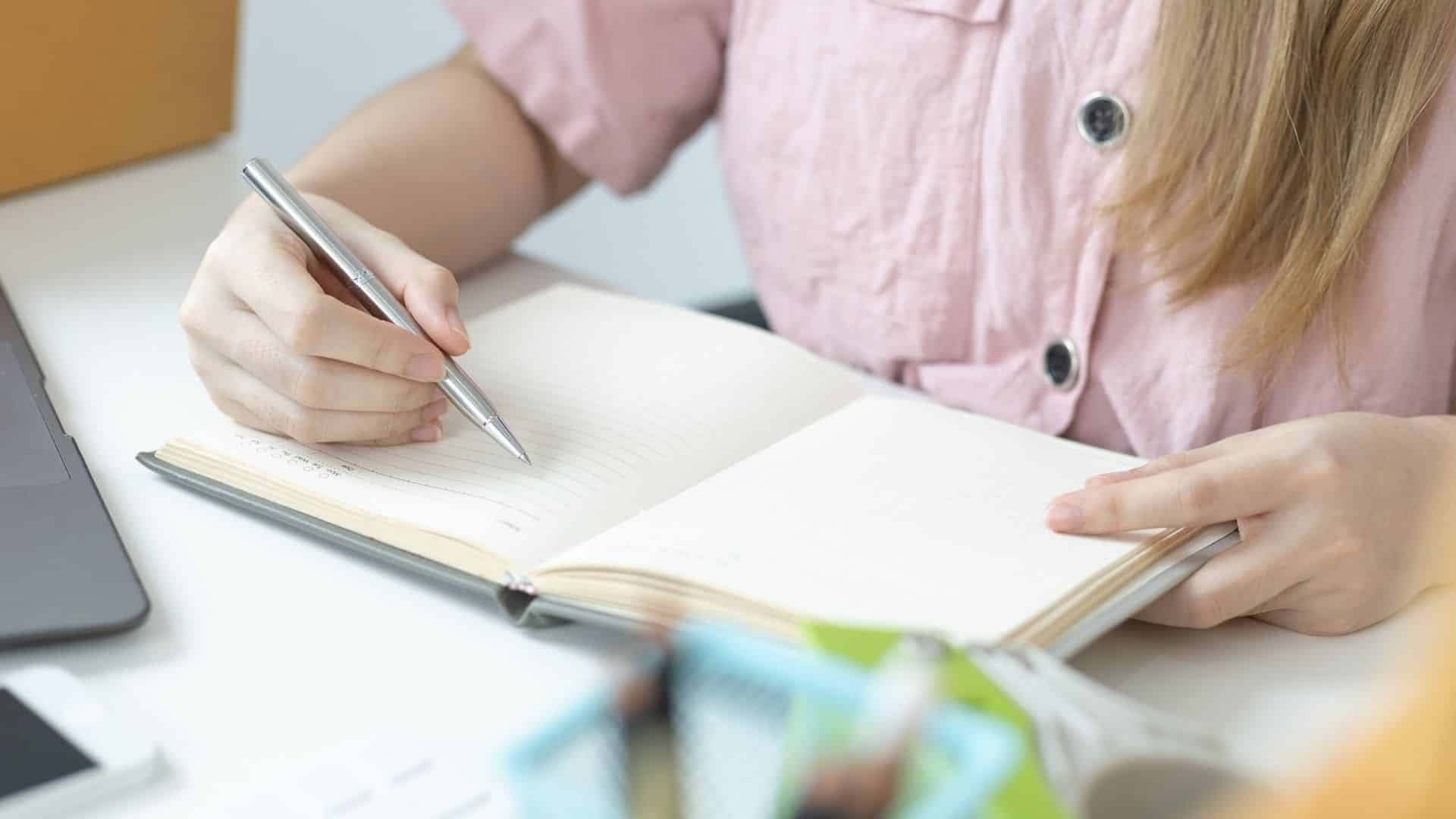 Uma mulher realizando anotações em um caderno.