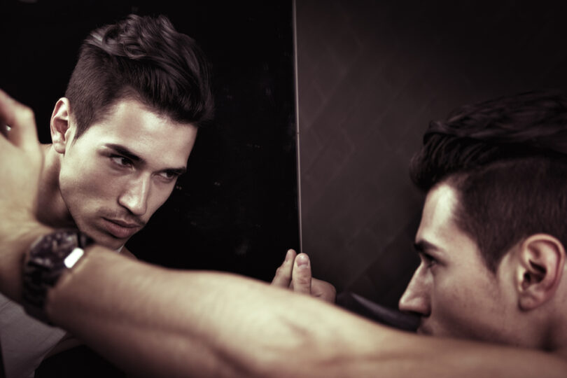 Um homem se olhando num espelho.