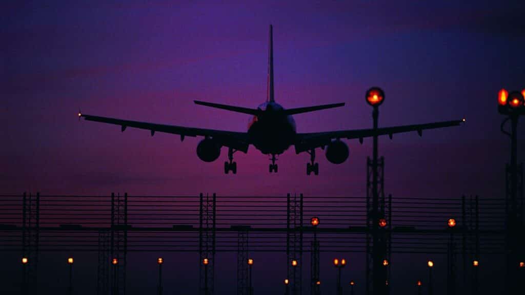 Um avião pousando num aeroporto durante a noite.