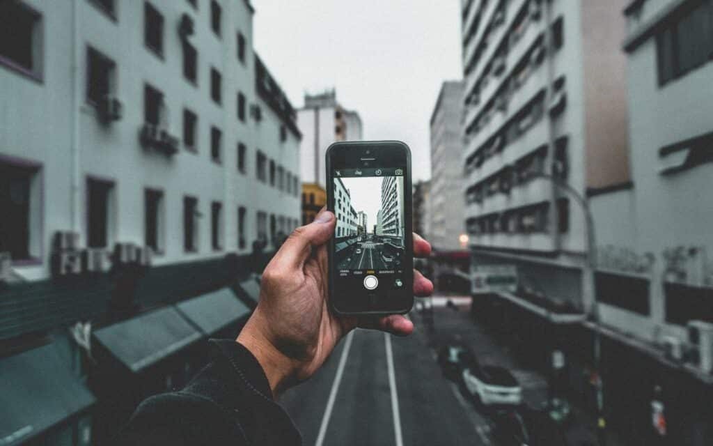 Uma mão masculina capturando uma fotografia num celular.