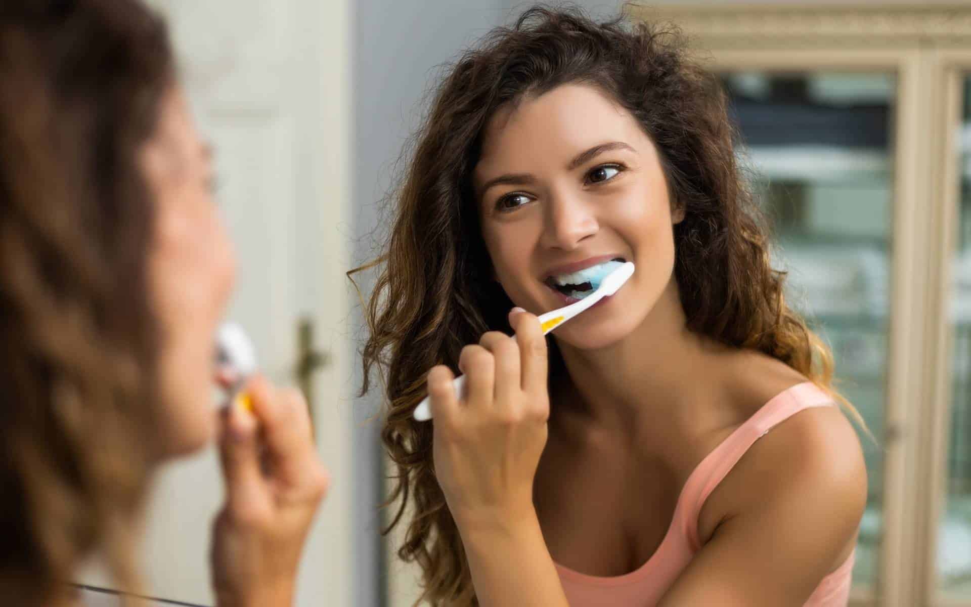 Uma mulher escovando dentes.